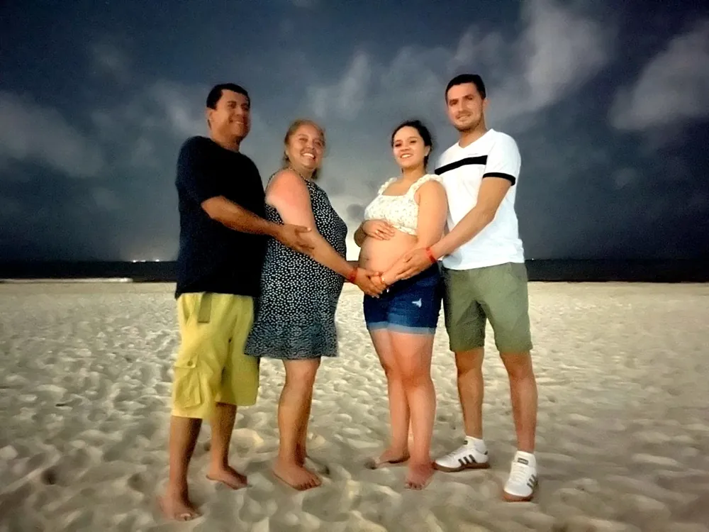 Nuestra familia en la playa, con las manos sobre el vientre de mamá